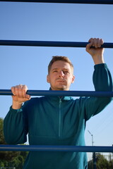 Naklejka premium A dedicated young athlete puts in the hard work, vigorously training on gym equipment outdoors to prepare his body. He builds strength and endurance before hitting the field or court for competition