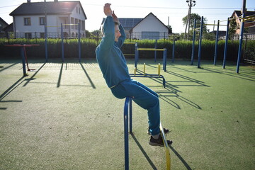 A dedicated young athlete puts in the hard work, vigorously training on gym equipment outdoors to...