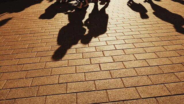 Shadows of people walking on street pavement in sunset, slow motion