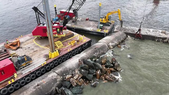 Using a grapple, a crane moves pieces of riprap to build up a pier in Algoma, WI on Lake Michigan.
