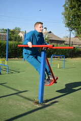 A dedicated young athlete puts in the hard work, vigorously training on gym equipment outdoors to...
