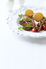 Grilled pork steak with vegetables. White wooden background. Close up. Copy space.