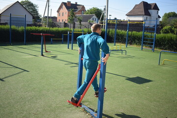 A dedicated young athlete puts in the hard work, vigorously training on gym equipment outdoors to...