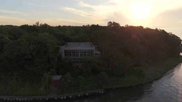 Aerial view of a party room surrounded by a green environment, with an amazing sunset over the Paran&aacute; River in the background, Misiones, Posadas.