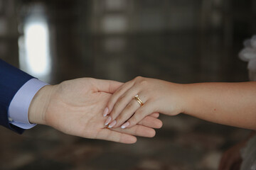 A close-up of the bride and groom holding hands, highlighting the sparkling engagement ring on the bride's finger.