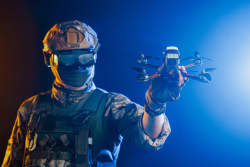 A soldier is depicted holding a drone while wearing stealth gear for military operations