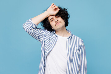 Young sad sick ill man he wearing shirt white t-shirt casual clothes put hand on forehead suffer from headache isolated on plain pastel light blue cyan background studio portrait. Lifestyle concept.