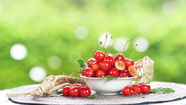 Red Cherry fruit on blurred greenery background, Red highest variety of cherries in white bowl on wooden table in the garden.