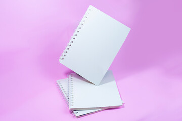 Three white notebooks on a pink background.