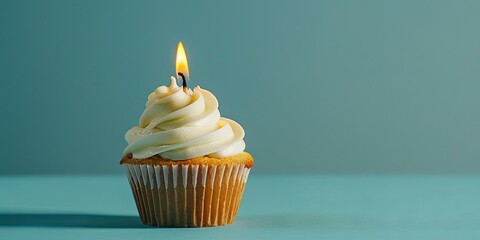 Single cupcake with lit candle on blue background. Concept of birthday, celebration, anniversary, party