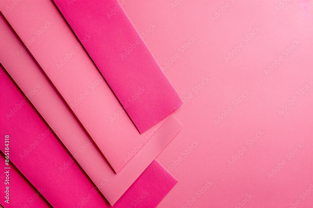 Poster a flat lay of three pink paper sheets arranged at an angle, creating geometric shapes on the solid c
