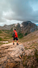 Obraz premium A young man admiring the majesty of the Bisaurín Peak, surrounded by the impressive landscapes of the Selva de Oza and the Western Valleys, a natural spectacle of incomparable beauty. 