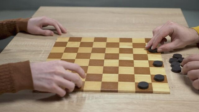 Men putting checkers on checkerboard. Home game concept. hobby. checkers on playing field