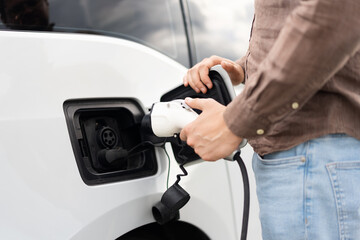 Person Charging Electric Car With Charger Plug, Sustainable Energy