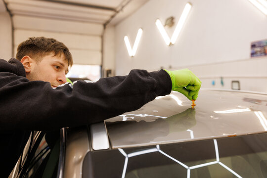 A professional car repair technician working on a vehicle in a garage with focus and precision