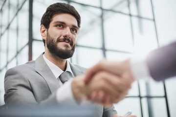 Two diverse professional business men executive leaders shaking hands at office meeting