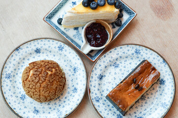 Piece of blueberry crepe cake with blueberry jam, choux cream and espresso macadamia cheese cake topped with coffee beans on the plate.