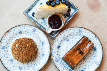 Piece of blueberry crepe cake with blueberry jam, choux cream and espresso macadamia cheese cake topped with coffee beans on the plate.