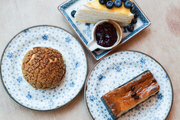 Piece of blueberry crepe cake with blueberry jam, choux cream and espresso macadamia cheese cake topped with coffee beans on the plate.