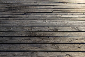 Fototapeta premium An old wooden pavement in sunset light as a background. Photo in perspective with selective focus