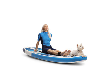 Woman in a wetsuit with a westie terrier dog resting on a SUP