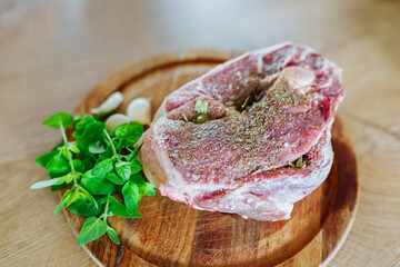 raw marinated lamb meat on a wooden round board with spices