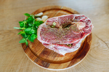 raw marinated lamb meat on a wooden round board with spices © larisikstefania
