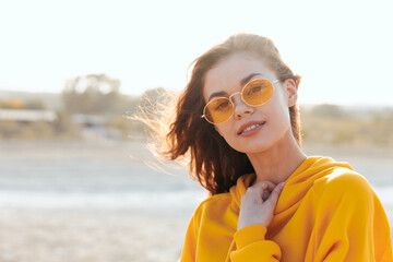stylish woman in yellow sweater and sunglasses soaking up sun on beach