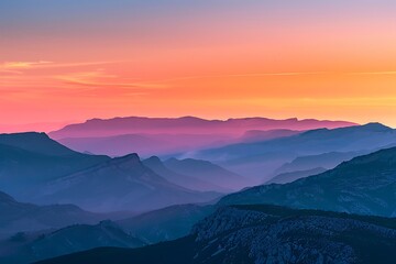 Vibrant hues of orange and pink dance across the sky as the sun sets behind a range of rugged mountains, casting a warm glow on the landscape.