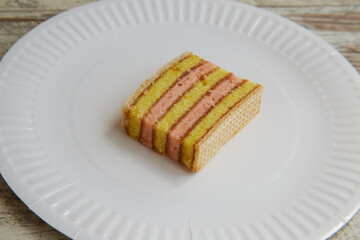 Yellow and pink sponge cake with waffles and jam on a white plate closeup