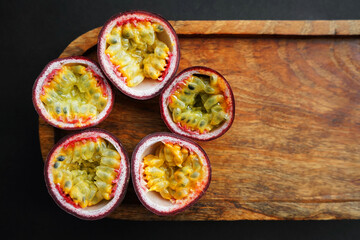 Passion fruits cut in half on a wooden tray on a dark background