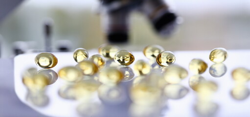 Tablets scattered yellow fish oil on table of the pharmaceutical laboratory pill for the prescription and treatment of various diseases chemistry