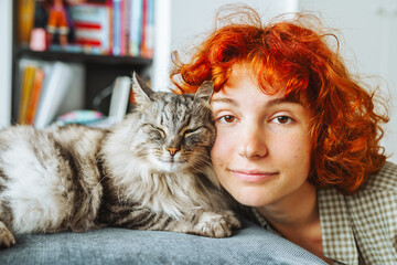 portrait red-haired attractive young woman with fluffy big cat © larisikstefania