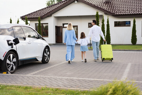 Family Arriving At Hotel With Electric Car, Carrying Luggage, Sustainable Travel
