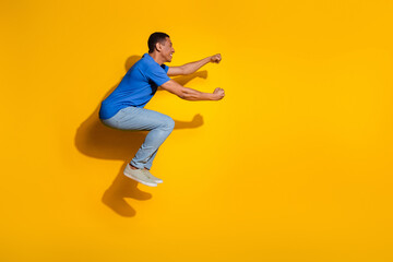 Fototapeta na wymiar Full length photo of handsome young guy jump drive invisible car dressed stylish striped garment isolated on yellow color background