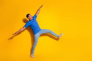 Fototapeta premium Full length photo of handsome young guy falling back keep balance dressed stylish blue garment isolated on yellow color background