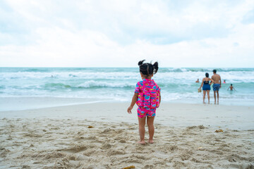 Adorable asian little toddler girl ejoying play toy on sand beach