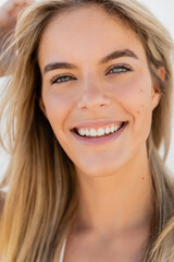 A young and beautiful blonde woman with long hair smiling at the camera on Miami Beach.