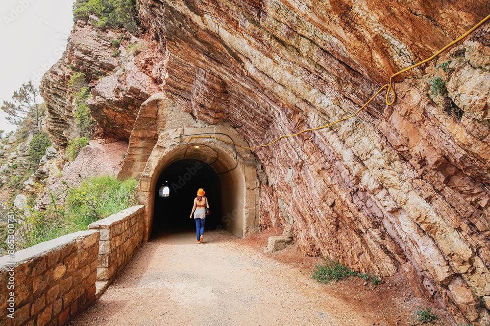 Wall mural Traveler exploring a mountain track with a tunnel entrance on the coastline of Petrovac, Montenegro