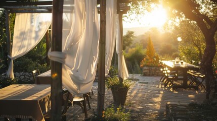 A long stretch of white fabric blowing in the wind creating a delicate curtain surrounding an outdoor eating area.