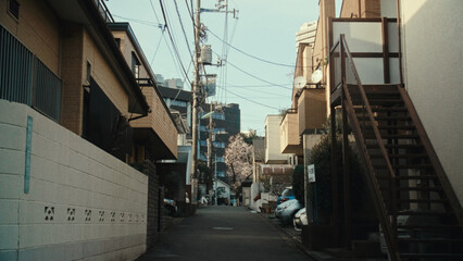 Quiet residential street in a Japanese neighborhood with power lines and buildings under a clear sky © Wirestock