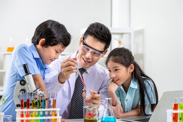 Enthusiastic Asian teacher guiding pupils in colorful science experiments in the laboratory science classroom