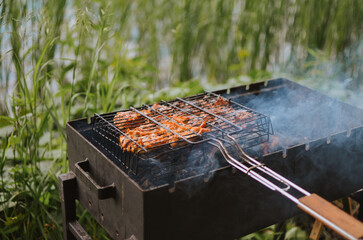 bbq shashlik with smoke on a grill in nature on a lake in summer