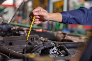 A mechanic in an auto repair shop is inspecting an engine. For customers who use their cars for repairs, the mechanic will work in the garage.
