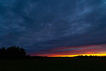 A beautiful summer sunrise in rural Latvia. Bright morning sky with dark foreground.