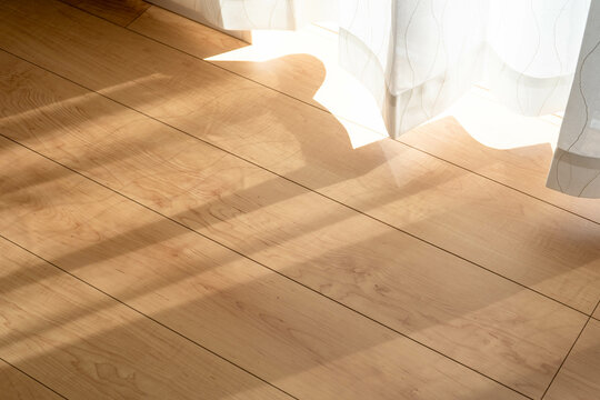 カーテンの隙間から太陽の光が差し込むマイホームのフローリング

