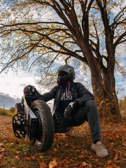 A man in a helmet is holding a monocycle. Electric monowheel is a modern urban transport. Riding in the autumn park © pavelkant
