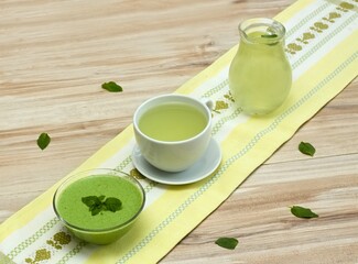 A cup and a jar of fresh tea, bowl with smoothie from Chickweed, lat. Stellaria media on the table.  Traditional herb tea rich in minerals is used for detoxificatin.