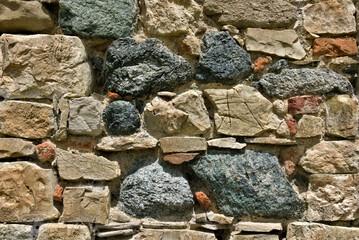 view of a wall of a rustic stone wall illuminated by the sun