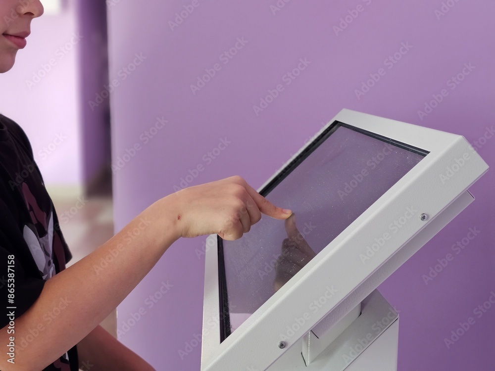 Wall mural teenager interacts with touch screen kiosk in purple room